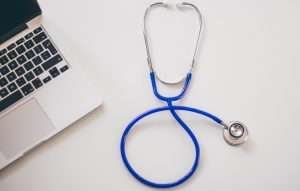 image of a blue stethoscope next to a laptop