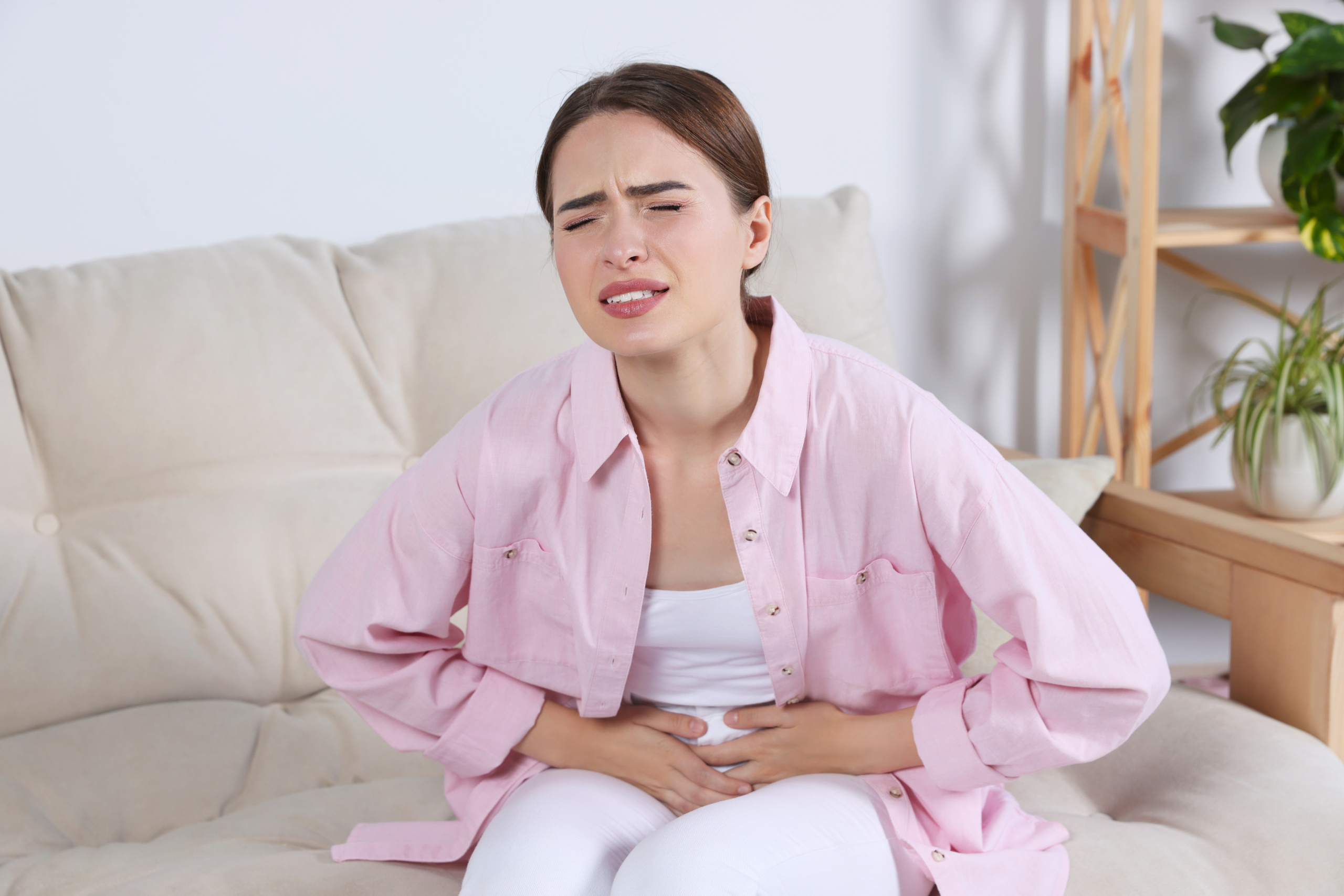 woman is holding her abdomen in pain due to UTI symptoms